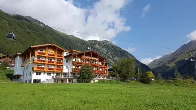 a building in a field next to a mountain at Alpenhotel Schönwald Superior in Valles