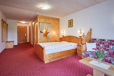 a bedroom with a bed and a couch at Alpenhotel Schönwald Superior in Valles