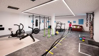 a gym with exercise equipment and a woman in a room at Feel good Resort Johannis in Tirolo