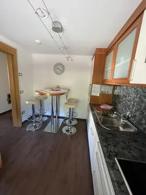 a kitchen with a table and two stools at Garnì Villa Erna in Selva di Val Gardena