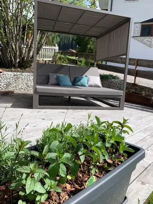 a couch sitting under a canopy in a garden at Garnì Villa Erna in Selva di Val Gardena