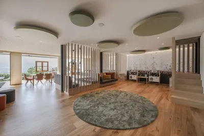 a living room with wooden floors and a large rug at Landsitz Stroblhof in Tirolo