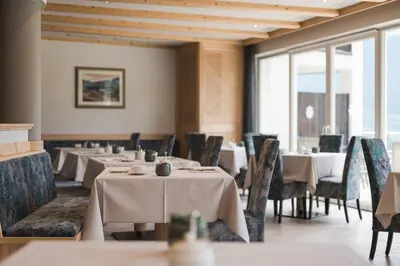 a dining room with tables and chairs and windows at Landsitz Stroblhof in Tirolo