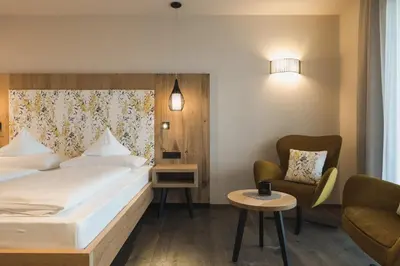 a hotel room with a bed and a chair at Landsitz Stroblhof in Tirolo