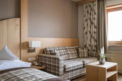 a living room with a couch and a bed at Landsitz Stroblhof in Tirolo