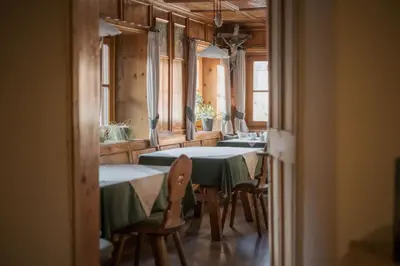 a dining room with tables and chairs and windows at Pension Moarhof in Feldthurns