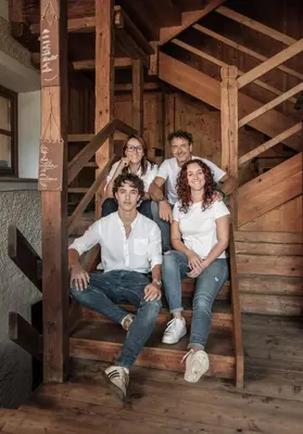 a group of people sitting on the stairs of a cabin at Pension Moarhof in Feldthurns