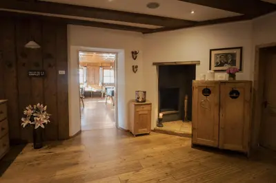 a living room with a fireplace and wooden floors at Pension Moarhof in Feldthurns