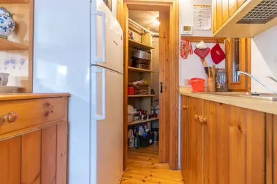 a kitchen with wooden cabinets and a white refrigerator at Villa Margherita in Moena