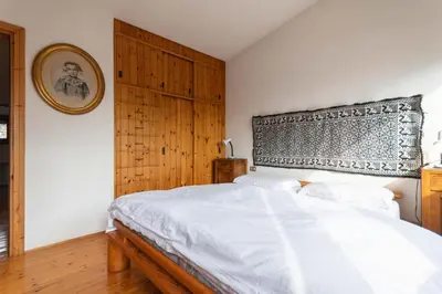 a bedroom with a white bed with a wooden headboard at Villa Margherita in Moena