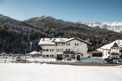 a house in the snow with mountains in the background at Residence As'Odei in San Cassiano