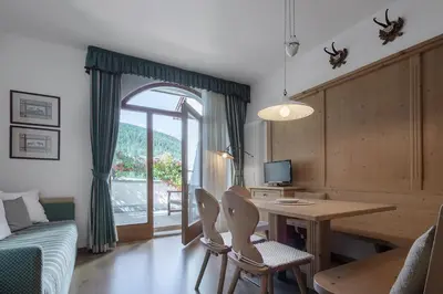 a living room with a desk and a table and chairs at Residence As'Odei in San Cassiano