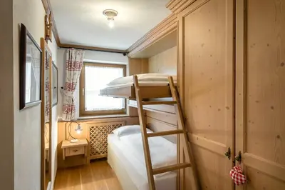 a bunk bed in a small room with a ladder at Residence As'Odei in San Cassiano