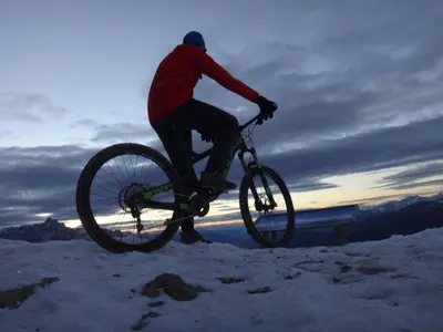 a man riding a bike in the snow at Hotel Serena in Badia