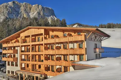 a large building with a mountain in the background at Hotel Serena in Badia