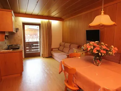 a living room with a table with a vase of flowers on it at Residence Rottonara in Corvara in Badia