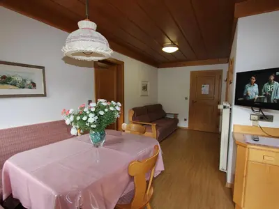 a dining room table with a vase of flowers on it at Residence Rottonara in Corvara in Badia