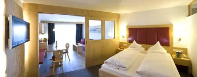 a bedroom with a bed with white sheets and a television at Martina Breakfast Lodge in Castelrotto