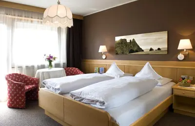 a hotel room with two beds and a chair at Martina Breakfast Lodge in Castelrotto