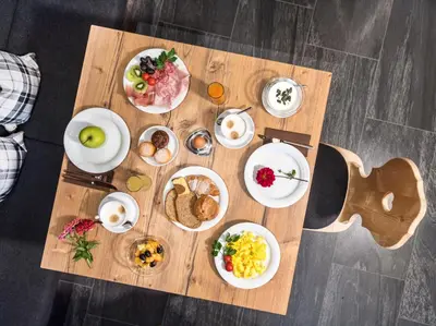 a wooden table with plates of food on it at Martina Breakfast Lodge in Castelrotto