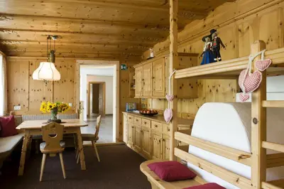 a log cabin kitchen and dining room with a bunk bed at Martina Breakfast Lodge in Castelrotto