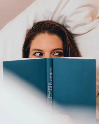 a woman laying in bed reading a book at Sensoria Dolomites in Siusi