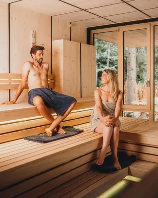 a man and a woman sitting in a sauna at Sensoria Dolomites in Siusi