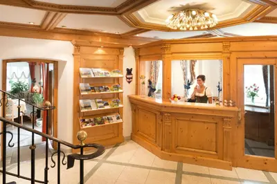 a woman standing behind a counter in a room at Hotel zum Wolf in Castelrotto
