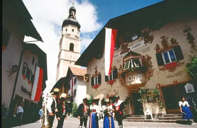 a group of people standing in front of a building with a clock tower at Hotel zum Wolf in Castelrotto