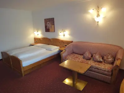 a hotel room with a bed and a couch at Hotel zum Wolf in Castelrotto