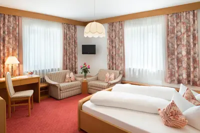 a hotel room with two beds and a desk and chairs at Hotel zum Wolf in Castelrotto