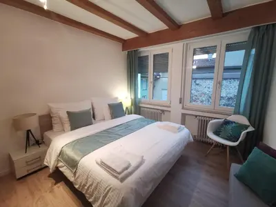 a bedroom with a large bed and two windows at City Apartment 221 in Merano