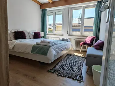 a bedroom with a bed and two windows and a rug at City Apartment 221 in Merano