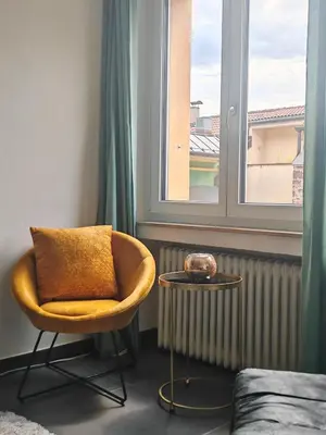 a chair and a table in a room with a window at City Apartment 221 in Merano