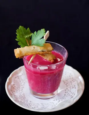 a pink drink on a plate with a garnishment at APIPURA hotel rinner in Soprabolzano
