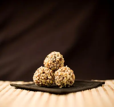 two chocolate covered peanut butter balls on a black plate at APIPURA hotel rinner in Soprabolzano