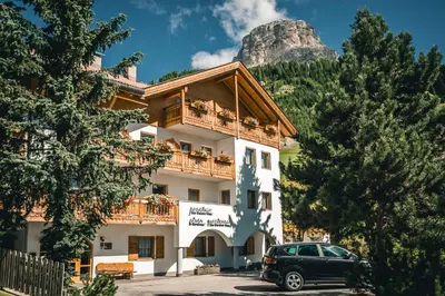 a building with a car parked in front of it at Pension Merisana in Colfosco