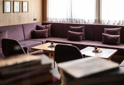 a living room with a couch and tables and chairs at Hotel Alpenroyal in Castelrotto