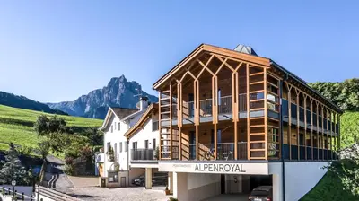 a building with a mountain in the background at Hotel Alpenroyal in Castelrotto