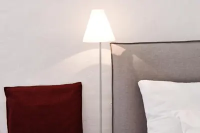 a lamp next to a bed with a red pillow at Casa Piganò in Appiano sulla Strada del Vino
