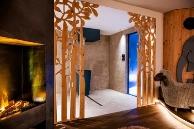 a living room with a fireplace and a room with a sheep at Family Hotel Posta in Santa Cristina in Val Gardena