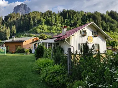 a white house with a mountain in the background at Family Hotel Posta in Santa Cristina in Val Gardena