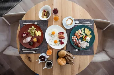 a wooden table with plates of breakfast food on it at Hotel Winkler Sport & Spa Resort in San Lorenzo di Sebato