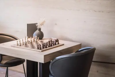 a chess board on a table with chairs and a vase at Hotel Winkler Sport & Spa Resort in San Lorenzo di Sebato