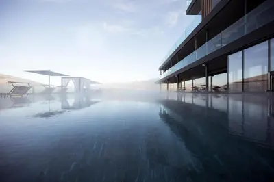 a pool of water in front of a building at Hotel Winkler Sport & Spa Resort in San Lorenzo di Sebato
