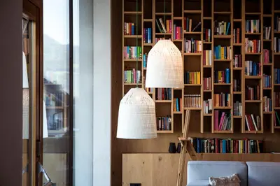 two lamps in front of a book shelf with books at Hotel Winkler Sport & Spa Resort in San Lorenzo di Sebato