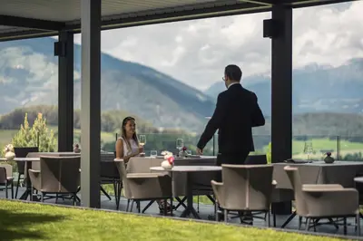 a man and a woman sitting at tables in a restaurant at Hotel Winkler Sport & Spa Resort in San Lorenzo di Sebato