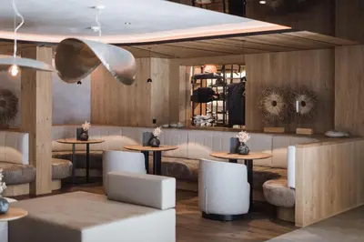 a restaurant with tables and chairs and a mirror at Hotel Winkler Sport & Spa Resort in San Lorenzo di Sebato