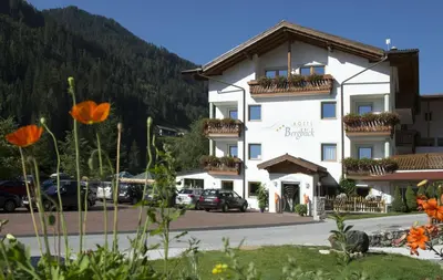 a large white building with cars parked in a parking lot at Hotel Bergblick in Racines