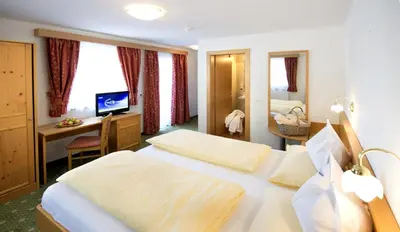 a hotel room with a large bed and a desk at Hotel Bergblick in Racines